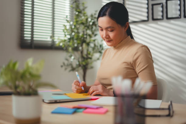 istock Asian woman enjoy with work and taking notes sitting at home office. 2203371238