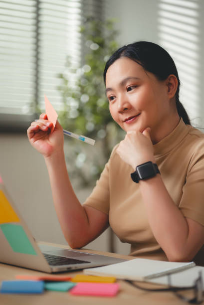 istock Asian woman enjoy with work and taking notes sitting at home office. 2203371404