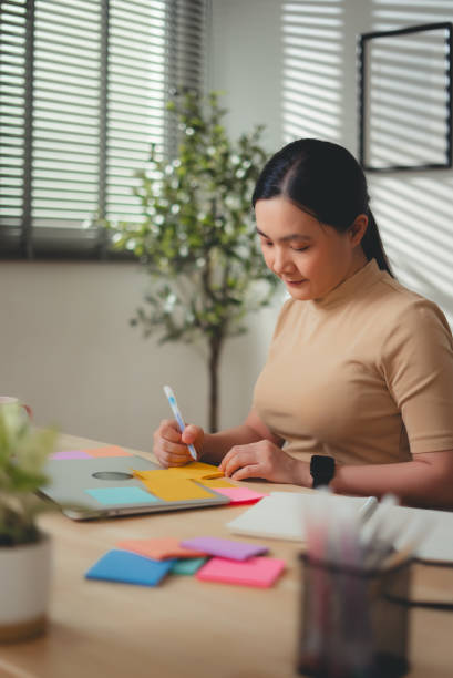 istock Asian woman enjoy with work and taking notes sitting at home office. 2203371964