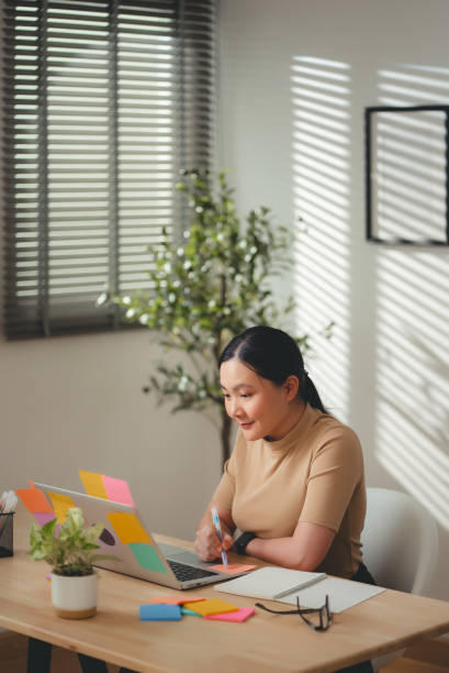 istock Asian woman enjoy with work and taking notes sitting at home office. 2203372328