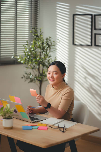 istock Asian woman enjoy with work and taking notes sitting at home office. 2203372392
