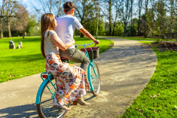 istock Young couple riding bicycle in a green park 2203372569