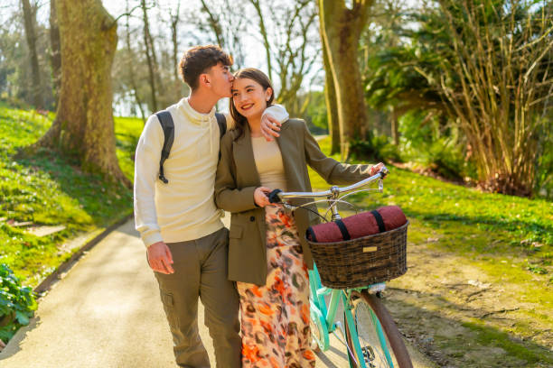 istock Young couple walking with bicycle in park on sunny day 2203372601