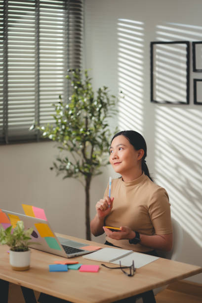 istock Asian woman enjoy with work and taking notes sitting at home office. 2203372713