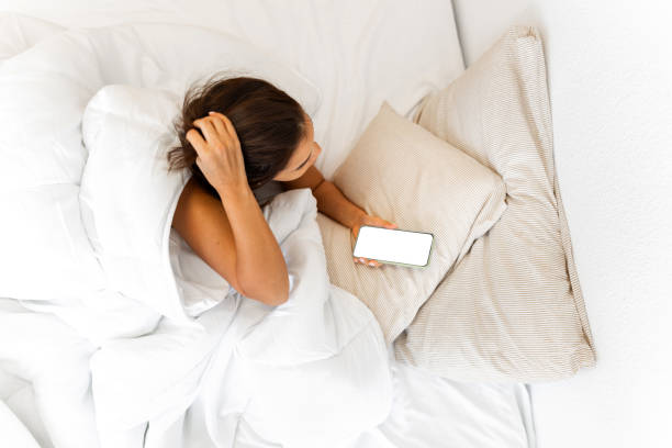 istock Woman lying in bed using smartphone with blank screen 2203372846