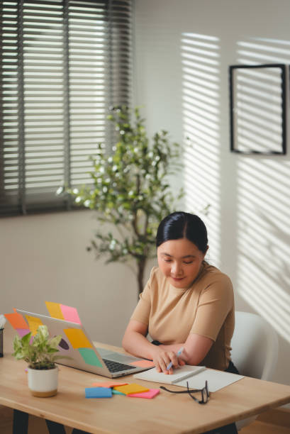 istock Asian woman enjoy with work and taking notes sitting at home office. 2203372876