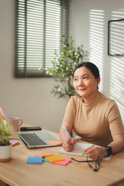 istock Asian woman enjoy with work and taking notes sitting at home office. 2203372903