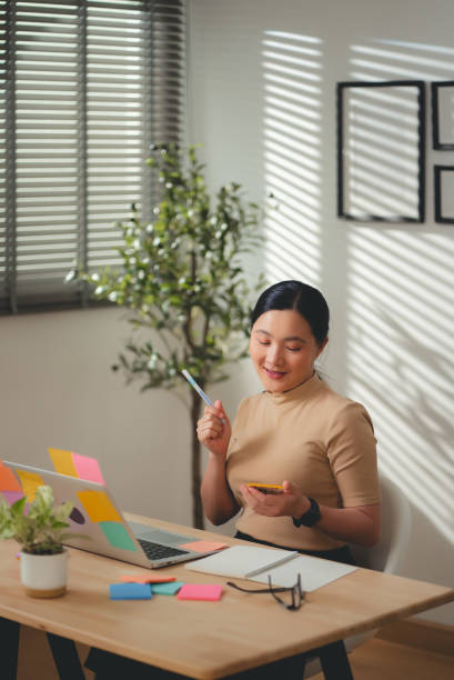 istock Asian woman enjoy with work and taking notes sitting at home office. 2203372947