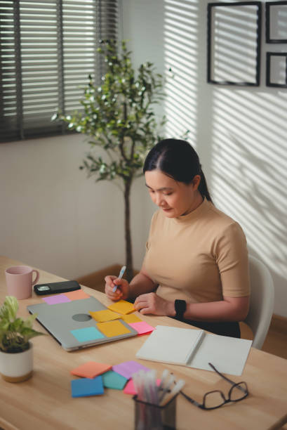 istock Asian woman enjoy with work and taking notes sitting at home office. 2203373099