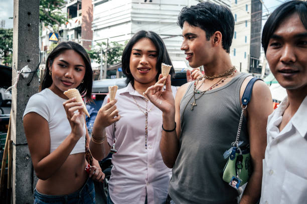 Group of LGBTQ friends talking together while eating ice cream cones on street