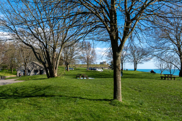 Weymouth, UK. 28 February 2025. People sat by the coast at Nothe Gardens in Weymouth