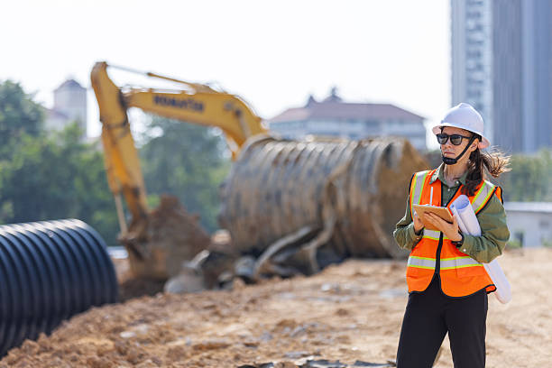 istock A female engineer  inspects a construction site with large drainage pipes and an excavator in the background. 2203374772