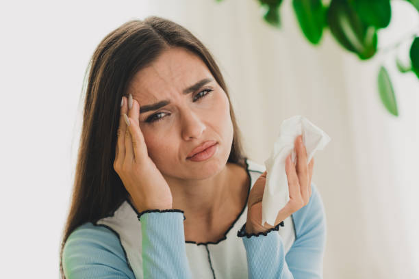 istock Young woman experiencing discomfort while holding a tissue indoors, expressing emotions in a bright living area with a casual 2203376324
