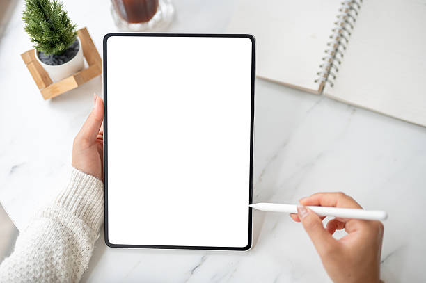 istock The left hand holding blank screen tablet with stylus pencil pointing at the screen in right hand. 2203376730