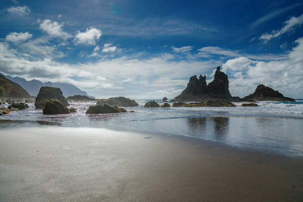 istock The breathtaking Playa Benijo shoreline with dramatic rock structures emerging from the water, serene reflections, and distant mountains, Tenerife 2203378105