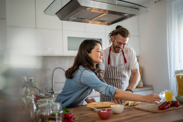 istock Happy couple preparing food and slicing bread in modern kitchen 2203379044