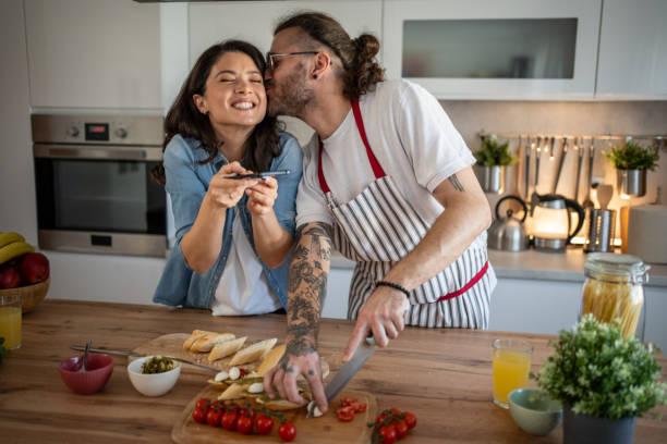 istock Man kissing woman while preparing meal in kitchen 2203379899