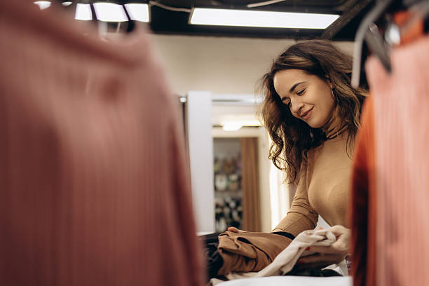 istock Smiling Woman Sorting Clothes in a Fashion Retail Setting 2203380446