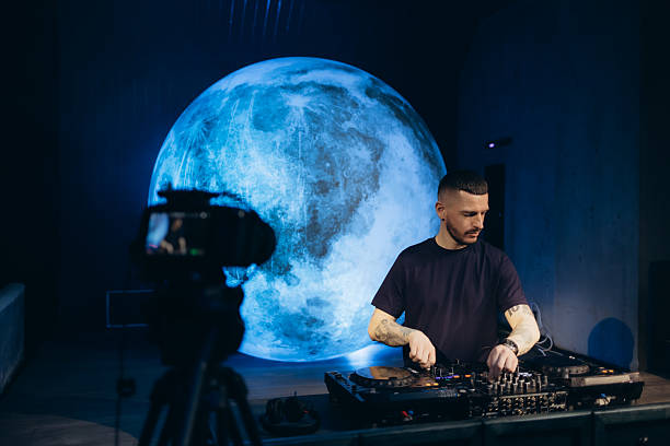 istock DJ Performing in Futuristic Setting with Large Illuminated Moon Backdrop 2203380447