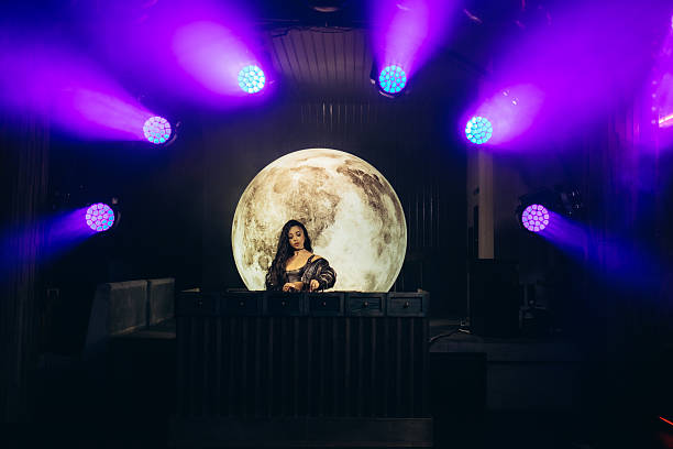 istock DJ Performing at Nightclub Stage with Moon Backdrop and Colorful Lighting 2203380453