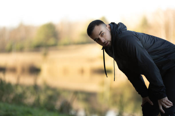 A young man catches his breath during an outdoor running workout.