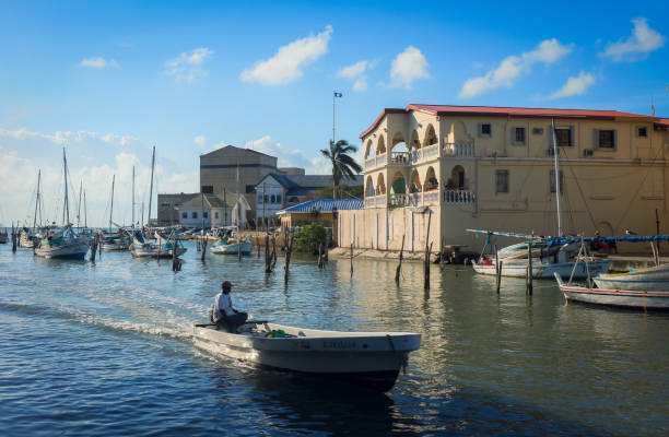 Belize City, Belize - January 19, 2025: Colorful boats glide through the calm waters of Belize City, showcasing local architecture and a vibrant atmosphere in the harbor.