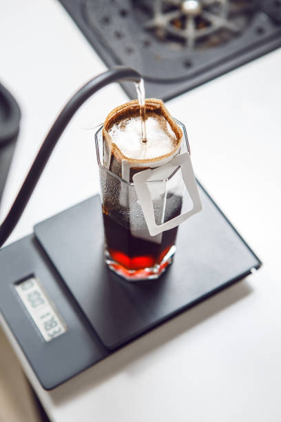 istock Hot Water is Poured Over a Coffee Drip Bag Resting on Scale for Precise Brewing Measurement, Close up 2203385516