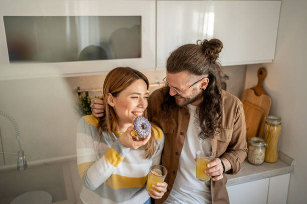 istock Happy couple enjoying breakfast with donuts and orange juice in kitchen 2203386509