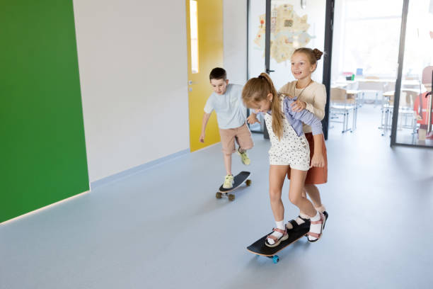Happy kids on skateboard at school hallway, having fun