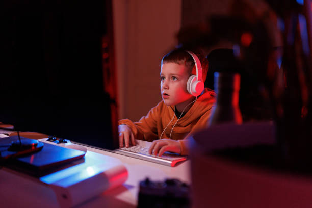 istock Little boy playing video game in the dark room 2203387683