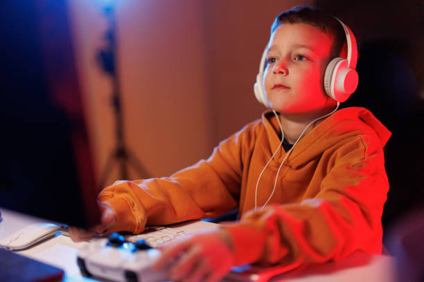 istock Boy playing video games in the evening at home 2203387712