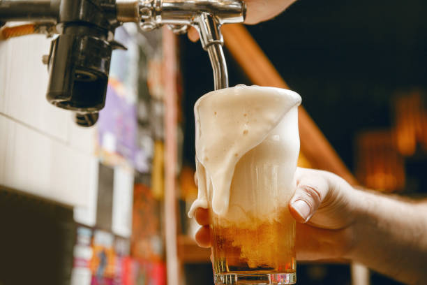 istock Bartender Skillfully Pouring Gold Beer With Rich Foam Into Glass 2203387829