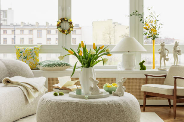 Bright living room with an Easter setup featuring yellow tulips in a white vase, soft textured pillows, and delicate decorations, creating a warm and festive ambiance.