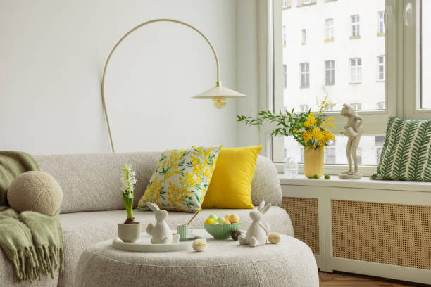 istock Bright living room with an Easter setup featuring yellow tulips in a white vase, soft textured pillows, and delicate decorations, creating a warm and festive ambiance. 2203387879