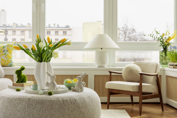 istock Bright living room with an Easter setup featuring yellow tulips in a white vase, soft textured pillows, and delicate decorations, creating a warm and festive ambiance. 2203387894