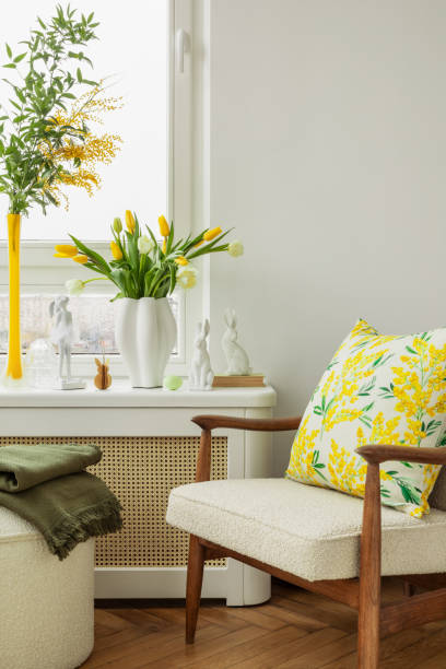 istock Bright living room with an Easter setup featuring yellow tulips in a white vase, soft textured pillows, and delicate decorations, creating a warm and festive ambiance. 2203387911