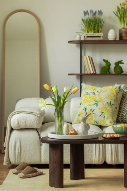istock Bright living room with an Easter setup featuring yellow tulips in a white vase, soft textured pillows, and delicate decorations, creating a warm and festive ambiance. 2203387925
