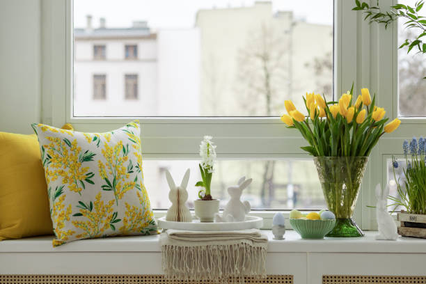 istock Bright living room with an Easter setup featuring yellow tulips in a white vase, soft textured pillows, and delicate decorations, creating a warm and festive ambiance. 2203388021