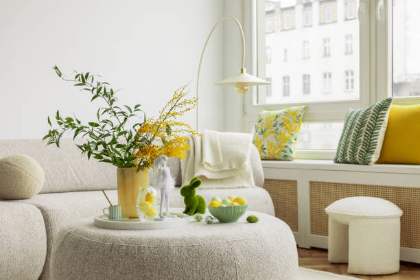 istock Bright living room with an Easter setup featuring yellow tulips in a white vase, soft textured pillows, and delicate decorations, creating a warm and festive ambiance. 2203388070