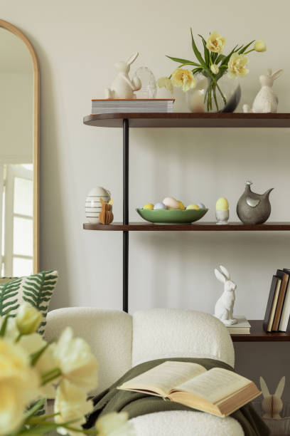 istock Easter decorations on a dark wood shelf, including ceramic bunny figurines, spring flowers, and pastel-colored eggs in a vintage bowl, creating a charming holiday display. 2203388118