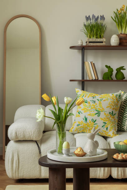 istock Elegant Easter setup with a stone frog sculpture, yellow tulips, and decorative eggs on a wooden side table. 2203388664