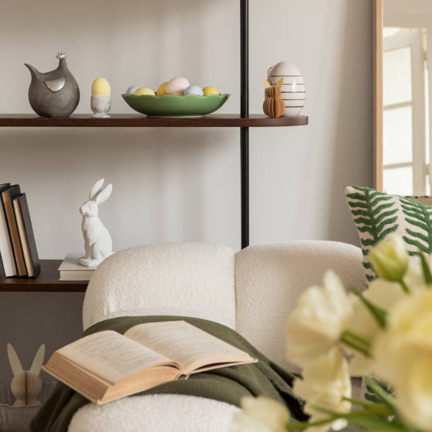 istock Easter table setting in a cozy living space with fresh yellow tulips, a white ceramic vase, and a decorative chicken figurine. A soft color palette and pastel accents create a festive atmosphere. 2203388910