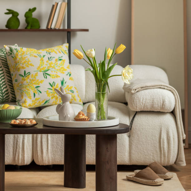 istock Bright living room with an Easter setup featuring yellow tulips in a white vase, soft textured pillows, and delicate decorations, creating a warm and festive ambiance. 2203388925