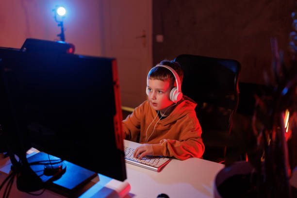 istock Little boy playing video game in the dark room 2203389024