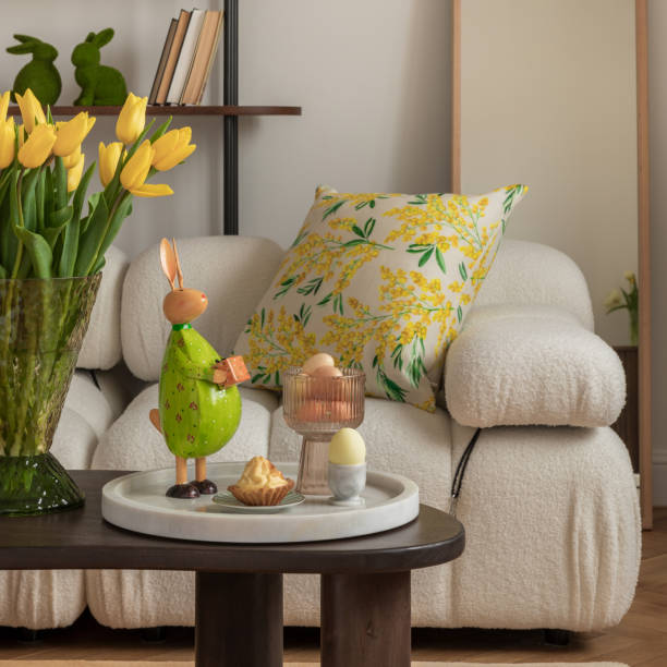 istock Easter table setting in a cozy living space with fresh yellow tulips, a white ceramic vase, and a decorative chicken figurine. A soft color palette and pastel accents create a festive atmosphere. 2203389039
