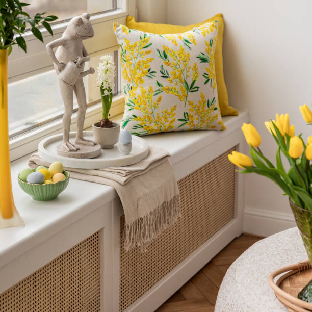 istock Bright living room with an Easter setup featuring yellow tulips in a white vase, soft textured pillows, and delicate decorations, creating a warm and festive ambiance. 2203389069