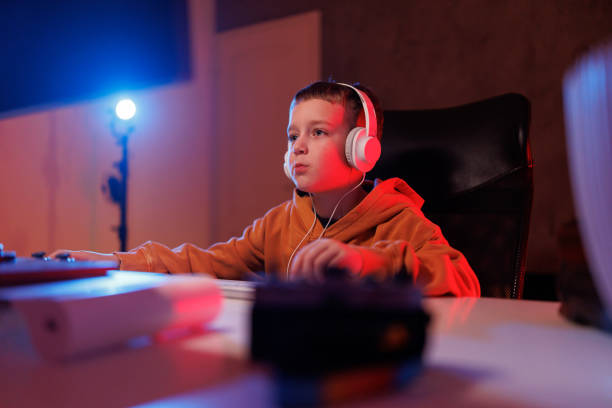 istock Little boy playing video game in the dark room 2203389369