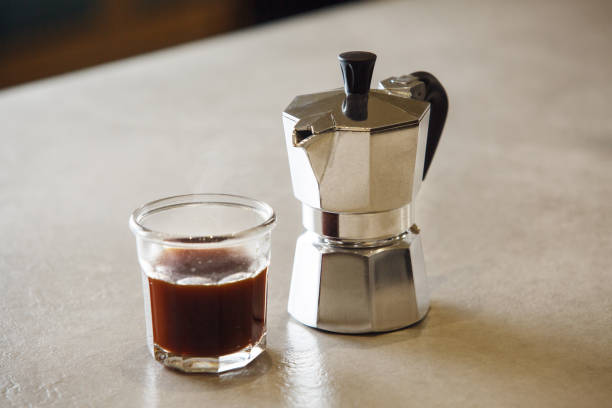 istock Brewed Espresso Served in Glass Cup Beside Traditional Italian Coffee Maker on Table 2203389990