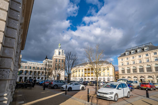 Poundbury, UK. 28 February 2025. Queen Mother Square in Poundbury near Dorchester with parked cars.