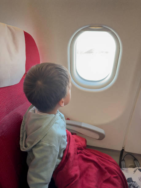istock Child in Airplane Seat Looking Outside Window 2203394869